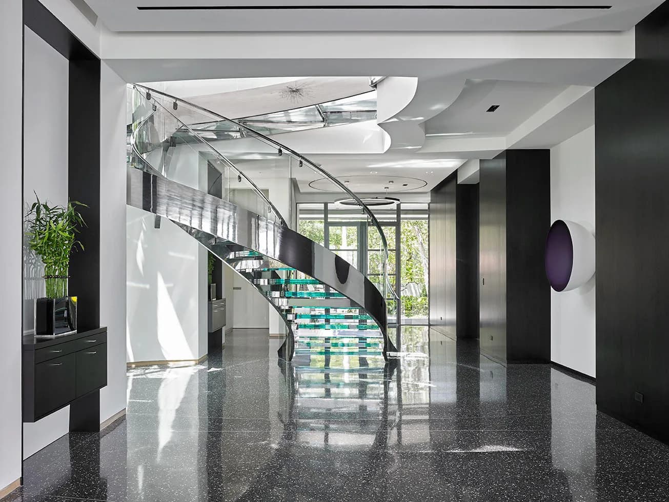 Contemporary Boca Raton villa foyer with a curved glass staircase over a terrazzo floor