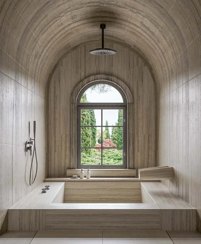 Vaulted travertine bathroom with an arched window
