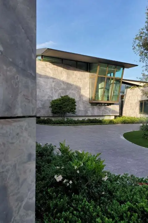 Stepping stone path leading to the glazed entrance, flanked by stone-clad walls