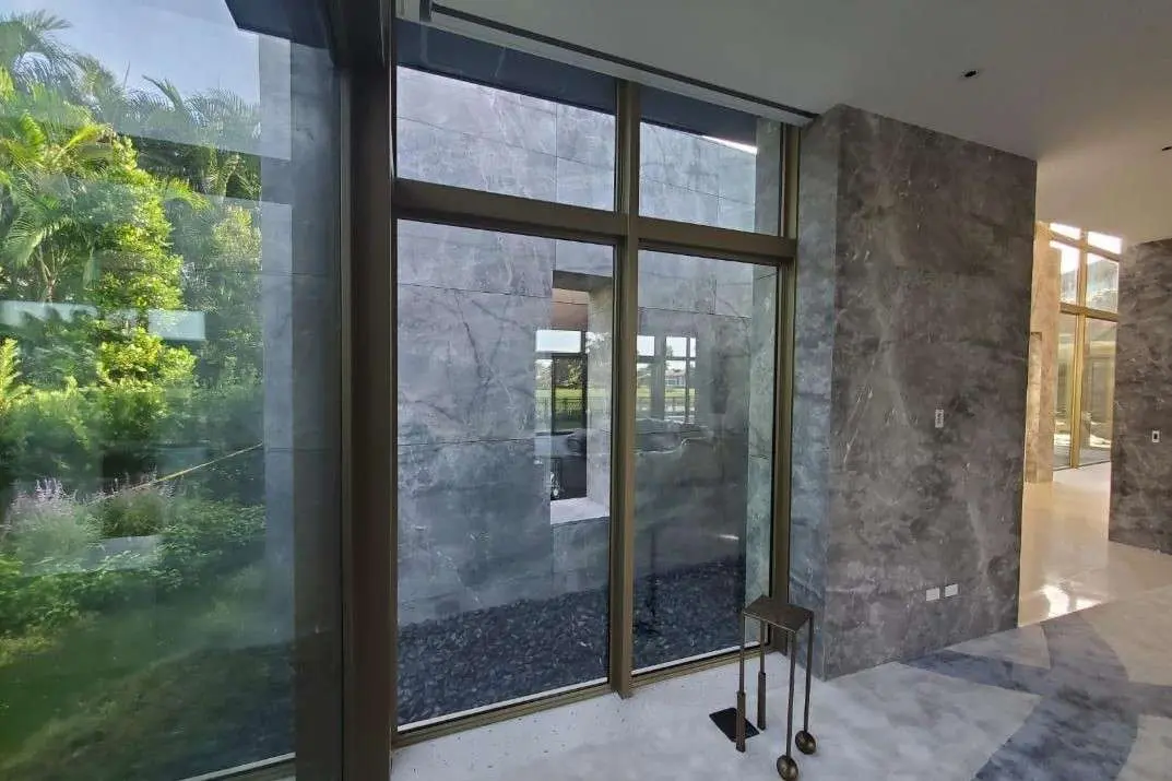 Corner of the house where full-height glazing meets the grey stone cladding