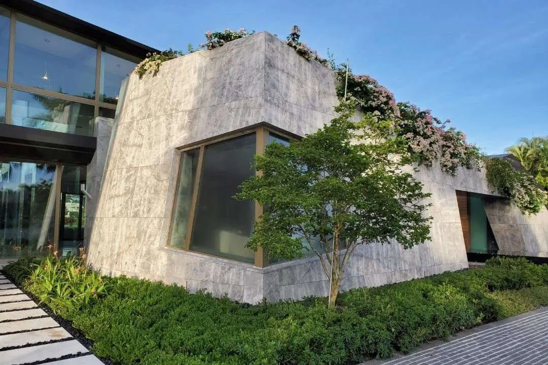 Angular stone-clad volume with a corner window and a mature tree in the foreground