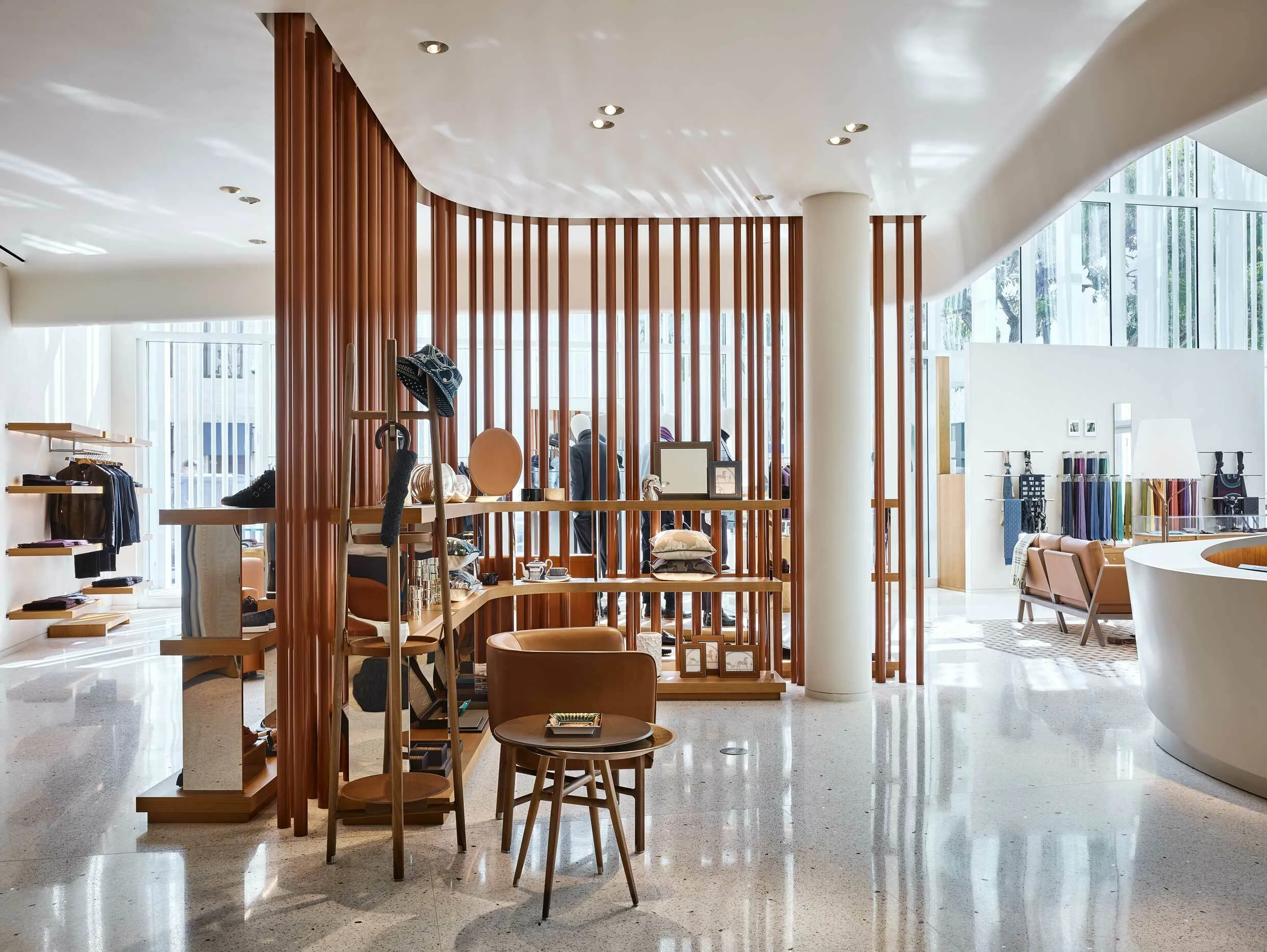 Bright Hermès Miami boutique interior with a wood slat partition and a terrazzo floor