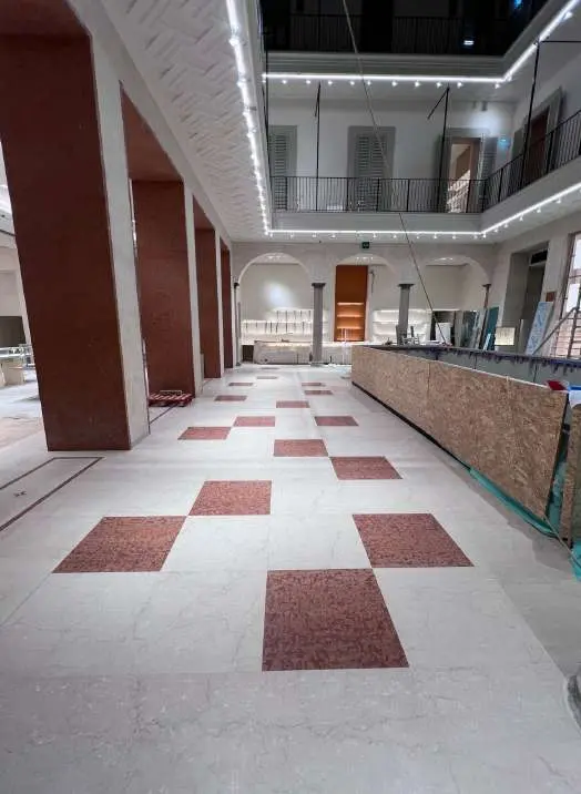Checkerboard marble floor being laid in a corridor