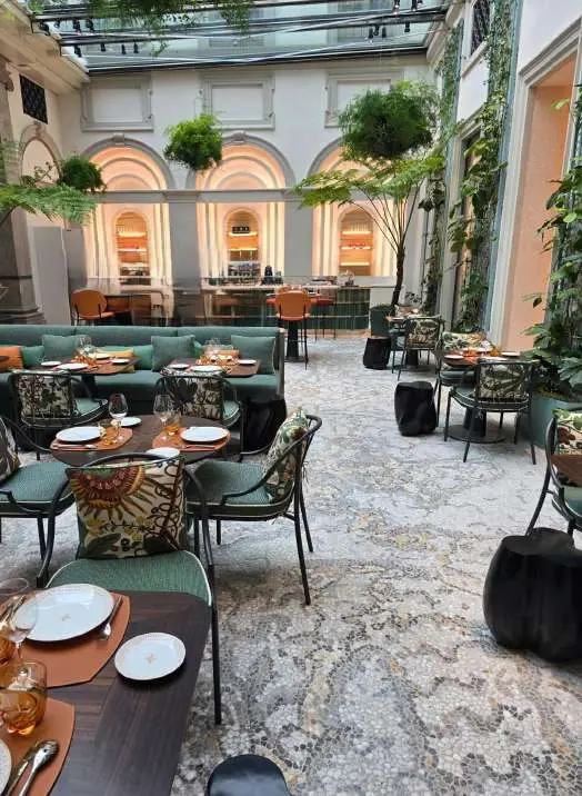 Glazed courtyard restaurant with a mosaic floor and green seating