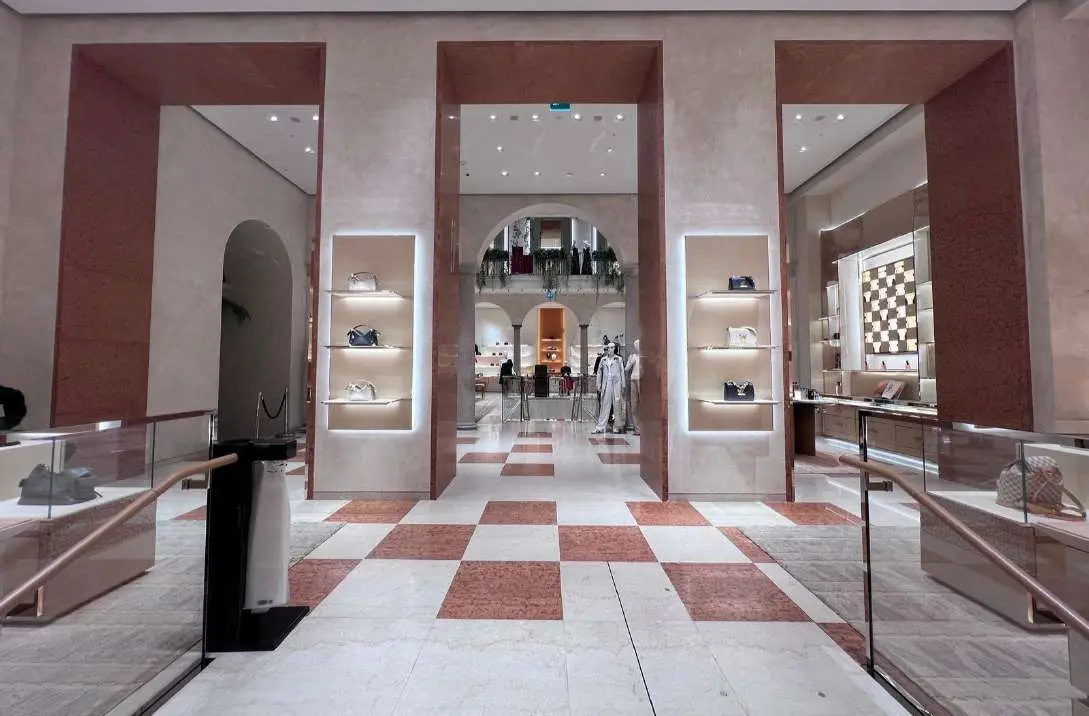Retail hall with a red and white checkerboard marble floor under arched openings