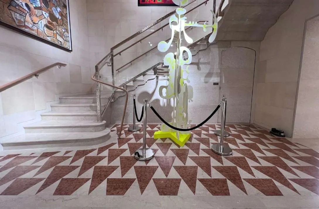 Hall with a red and white triangle marble floor and a chandelier