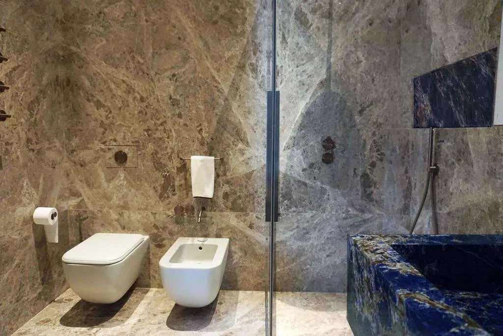 Bathroom in grey marble with a Lapislazuli basin and a glass shower in a Milan apartment