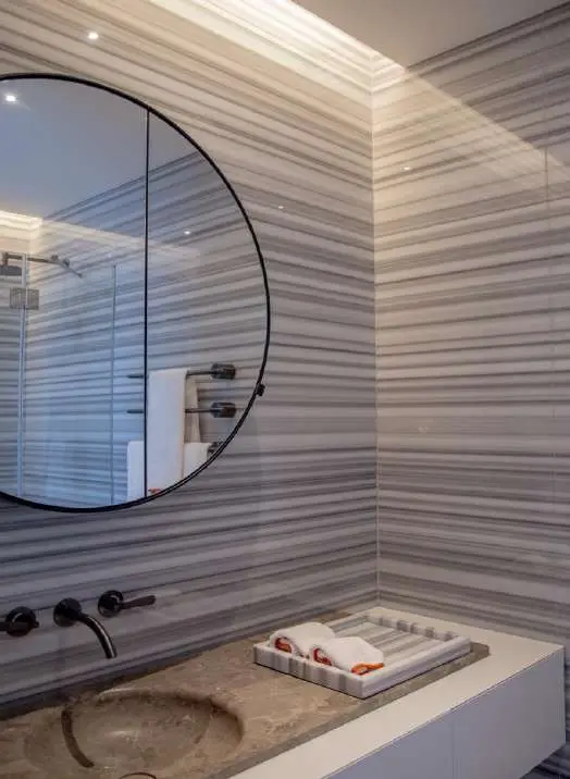 Shower lined in fluted Striato Olimpico with a round mirror