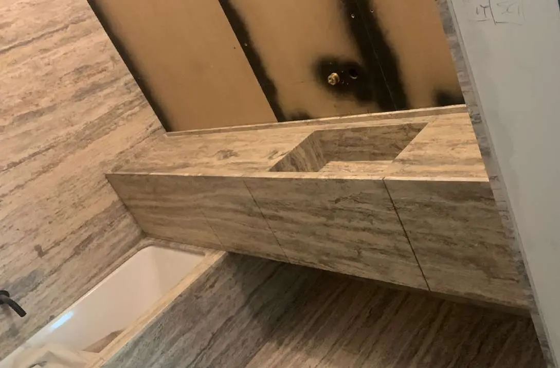 Bathtub set into a Travertino Silver surround with matching wall cladding