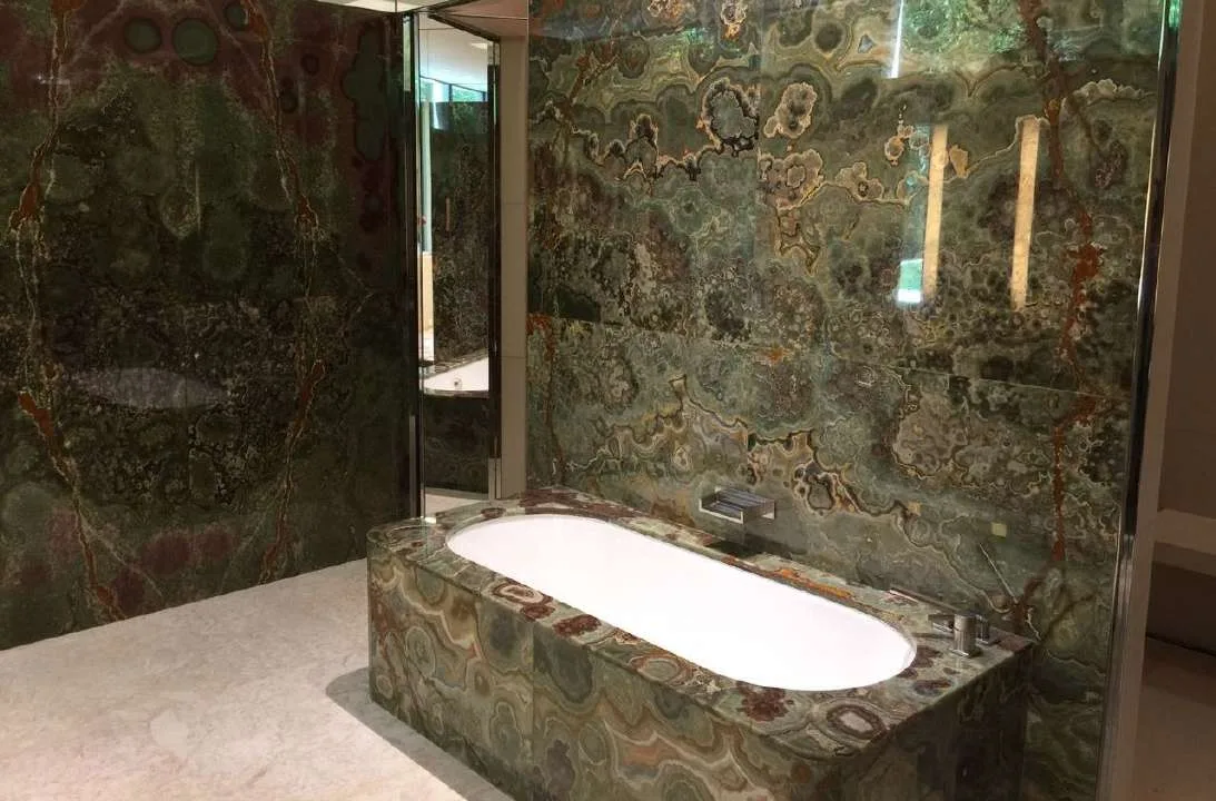 Master bathroom lined in bookmatched green onyx