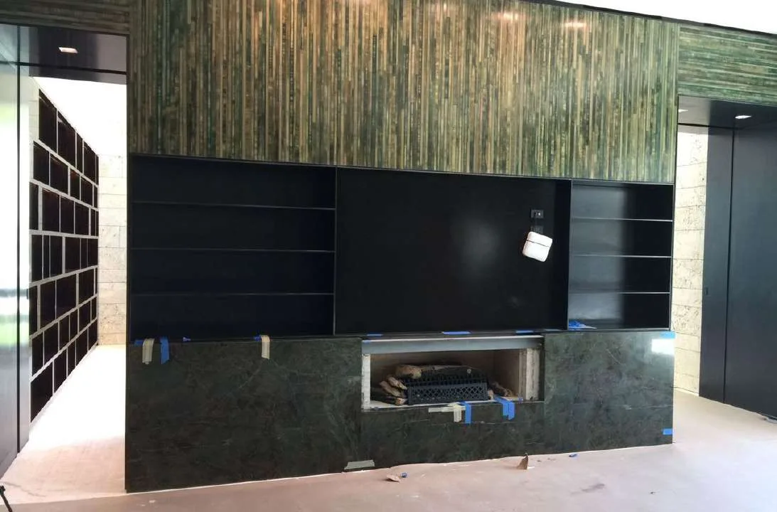 Living-space media wall in vertical green stone with integrated TV niche