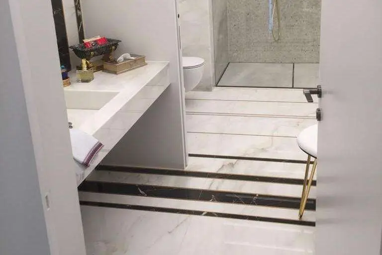 Bathroom floor in white marble with dark inlay strips near the vanity