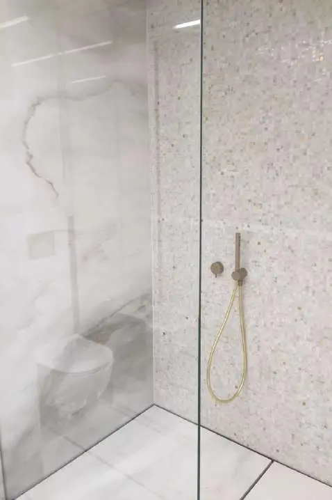 Marble-lined shower enclosure with a glass screen