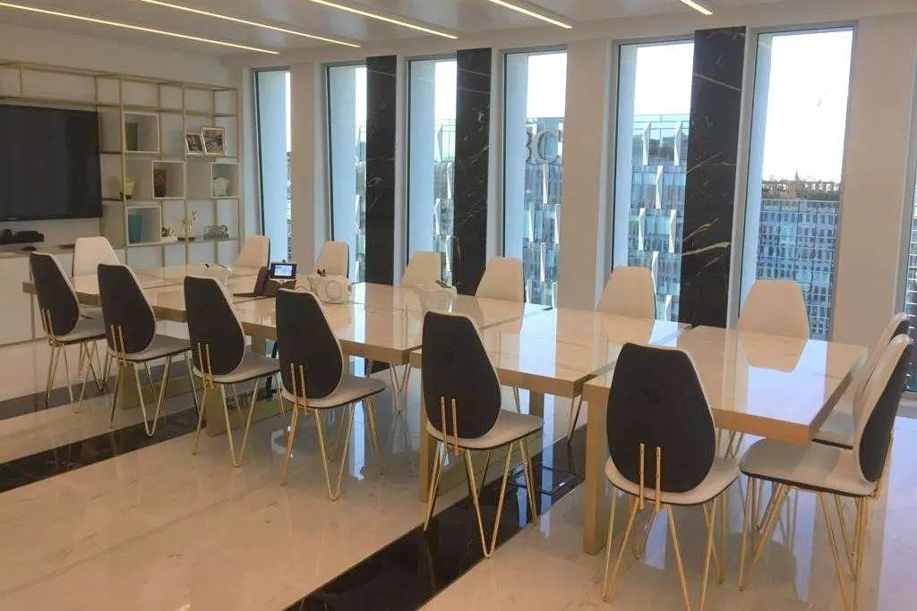 Boardroom with a long marble table and chairs in front of a full-height city window