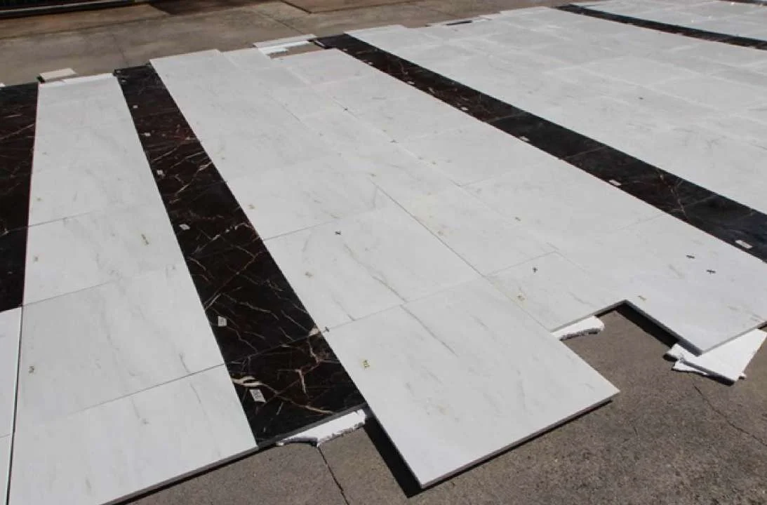 Marble floor panels dry-laid with dark inlay strips before installation
