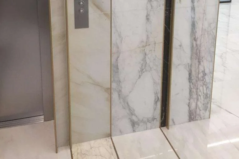 Elevator lobby clad floor to ceiling in white veined marble