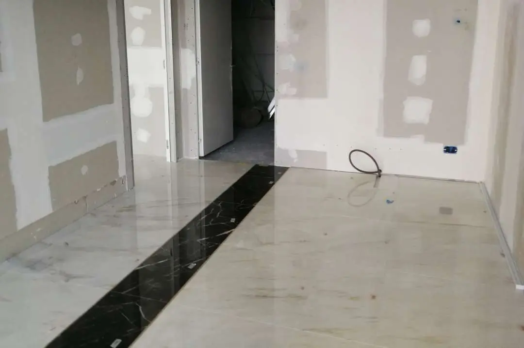 Installed marble floor with a dark inlay strip running through the room