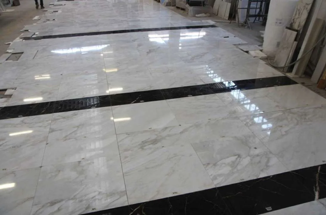 Marble floor being laid with dark inlay strips in an office space