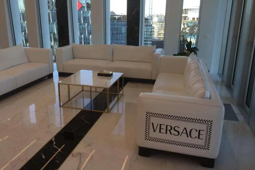 Lounge with white sofas on a marble floor with dark inlay strips, Versace branding on the sofa