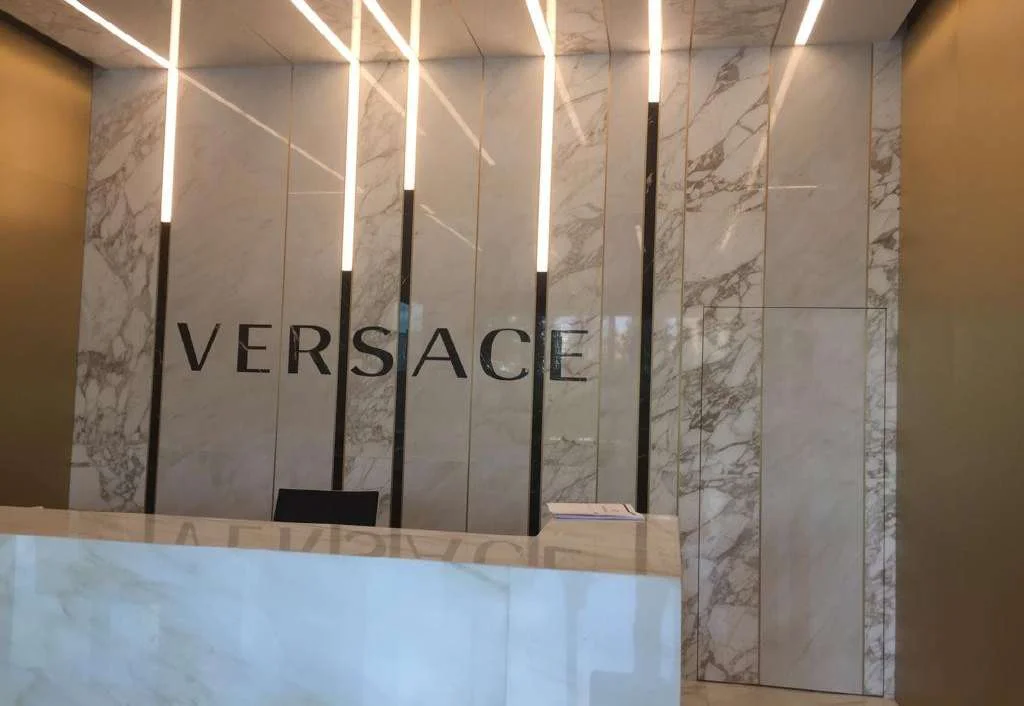 Versace office reception clad in Cremo Delicato marble with backlit Versace lettering