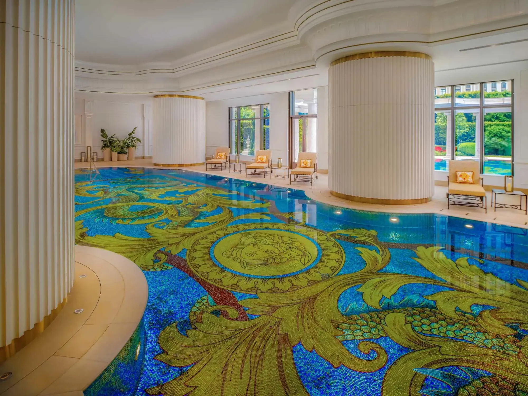 Indoor pool framed by marble mosaic walls and floor