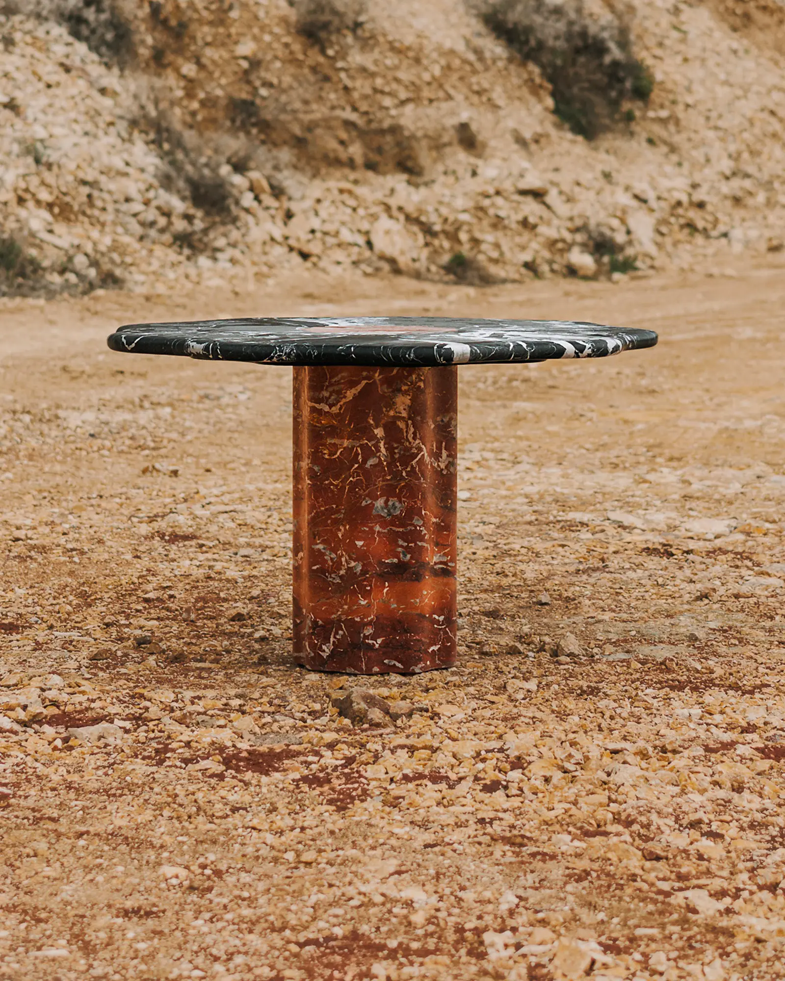 Round marble dining table with a scalloped top, set in a quarry